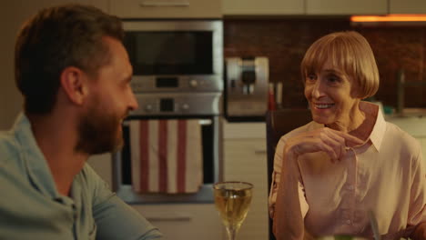 Adult-son-sitting-at-dining-table-with-senior-mother.-Family-having-conversation