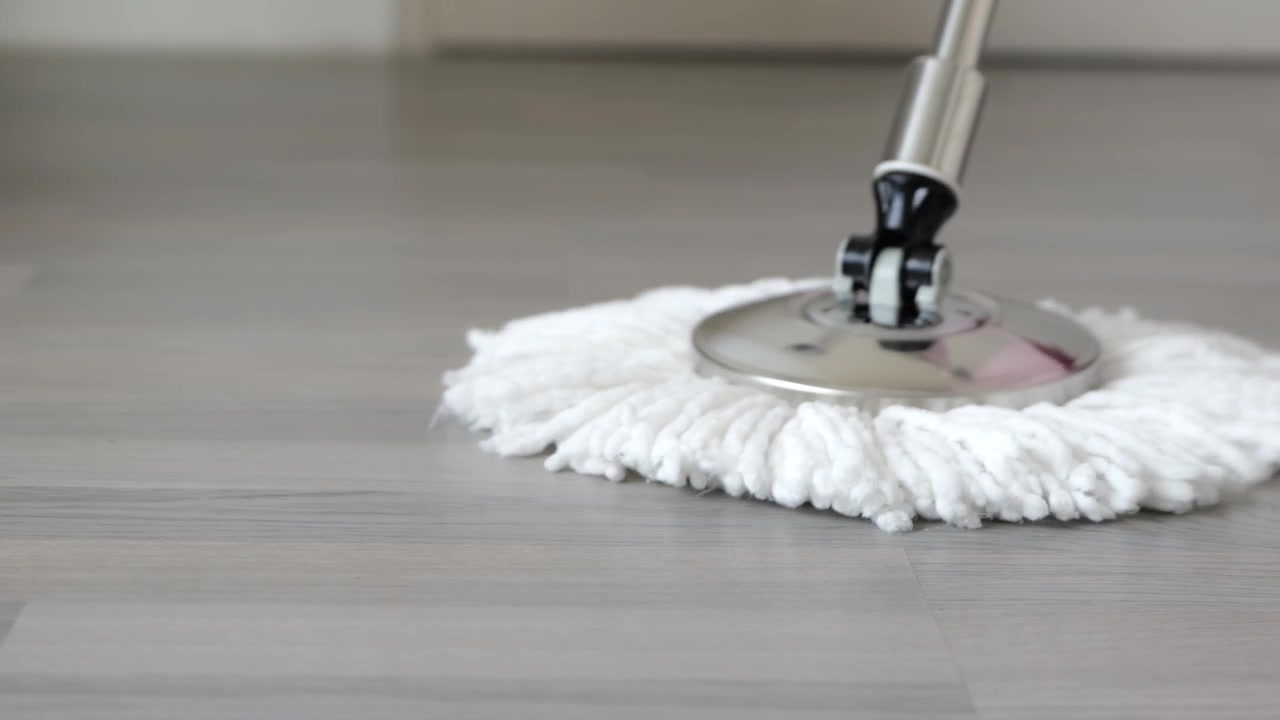 Primo piano di un mocio domestico che pulisce il pavimento, evidenziando la manutenzione della casa, la pulizia e l'igiene quotidiana in uno spazio abitativo moderno.