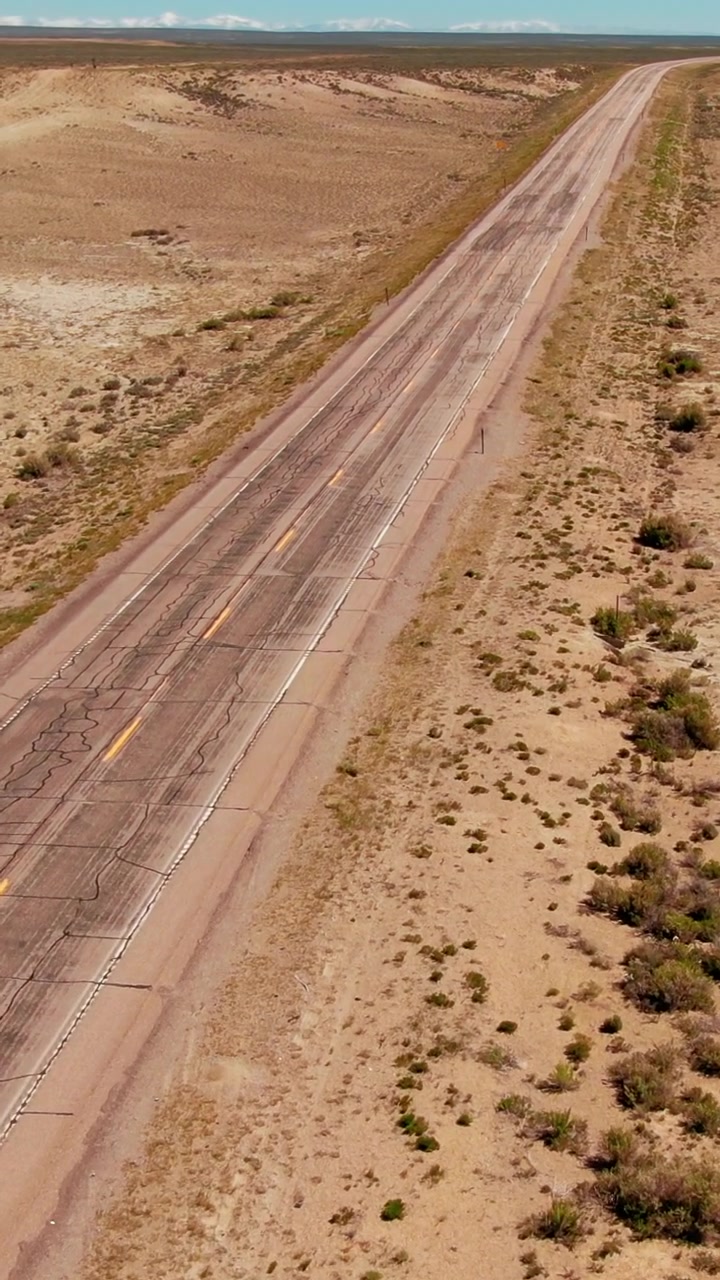 Uma estrada iluminada pelo sol se estende por um deserto árido em Wyoming, destacando o terreno seco. Ideal para conteúdo de viagem ou cenas que retratam isolamento.
