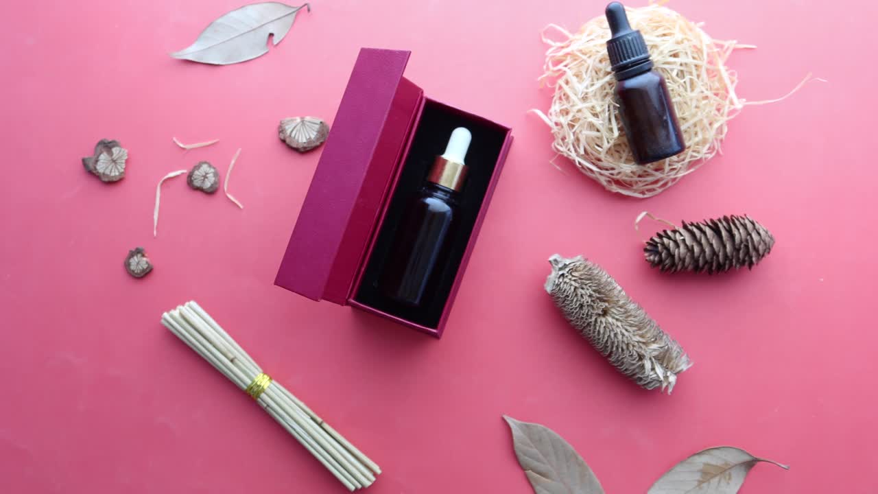 유리 병에 유칼립투스 에센셜 오일과 보라색 배경에 꽃