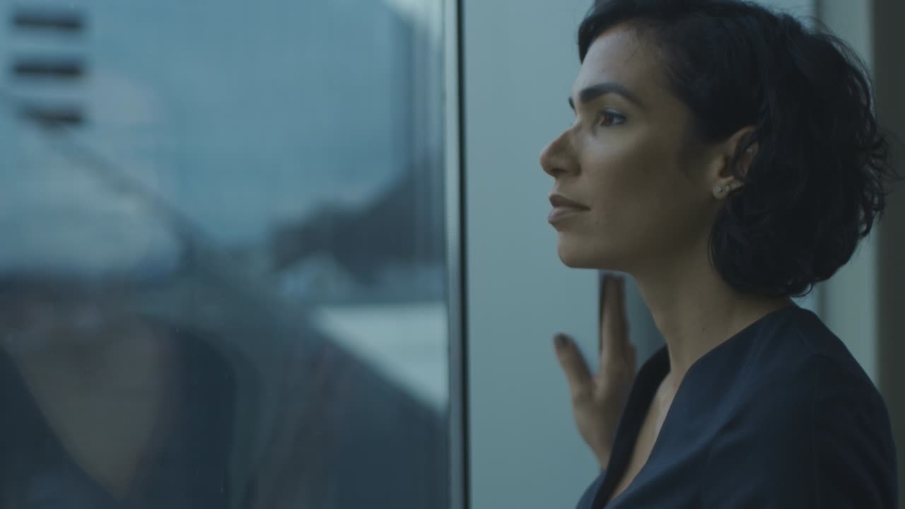 retrato en primer plano de la hermosa joven mujer de negocios mirando pensativa fuera de la ventana de su oficina con vista al paisaje urbano. mujer hispana segura y atractiva pensando en su proyecto de negocio.