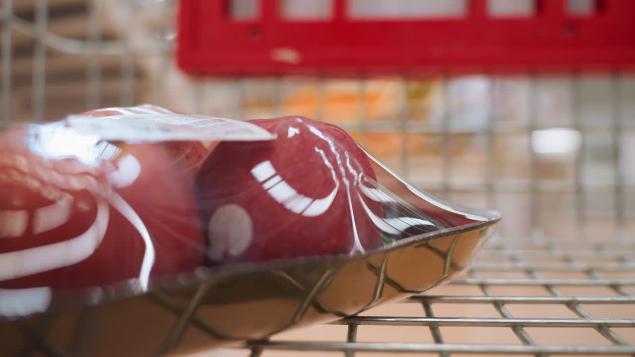 mele confezionate in un carrello della spesa in movimento, catturato in un centro commerciale. la scena enfatizza l'atto di fare la spesa, con una vista dinamica e coinvolgente fornita da una telecamera portatile