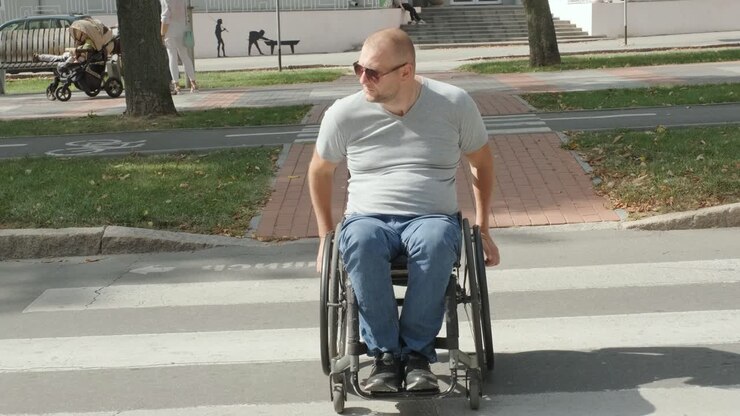 Man with disabilities in wheelchair crossing street road
