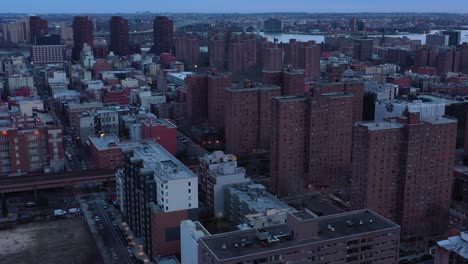 solemn and slow drone approach of housing projects in new york city's harlem neighborhood at sunset blue hour