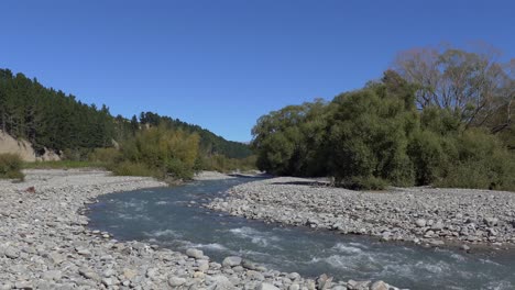 Langsamer-Spaziergang-In-Richtung-Flussbiegung-über-Steine-An-Einem-Schönen-Sommertag---Kowai-River,-Canterbury