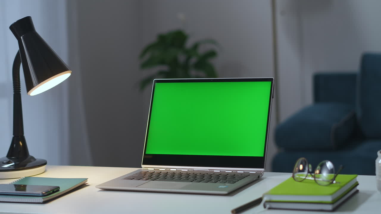 laptop con schermo verde sul tavolo di lavoro nell'ufficio di casa l'uomo sta accendendo le lampade da tavolo e da pavimento nel soggiorno