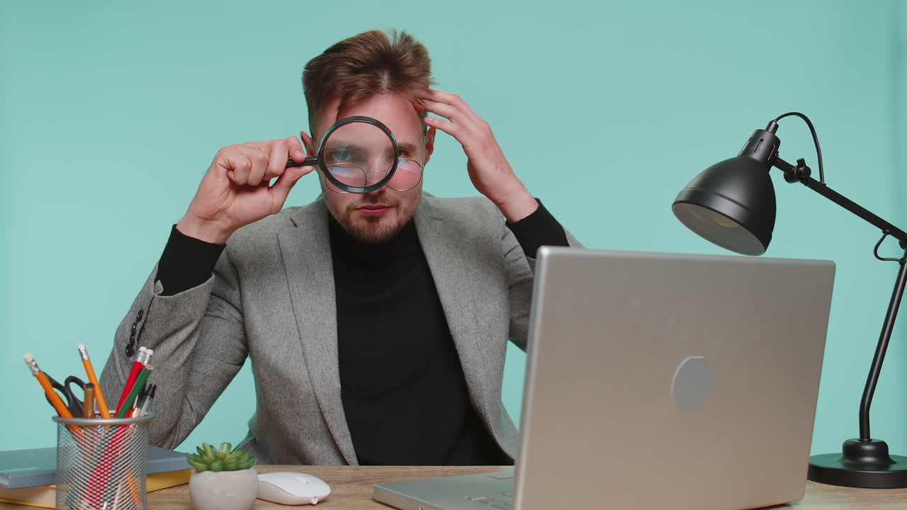Investigator researcher scientist businessman holding magnifying glass near face analysing searching