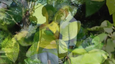 Animation-of-leaves-over-african-american-couple-working-in-garden