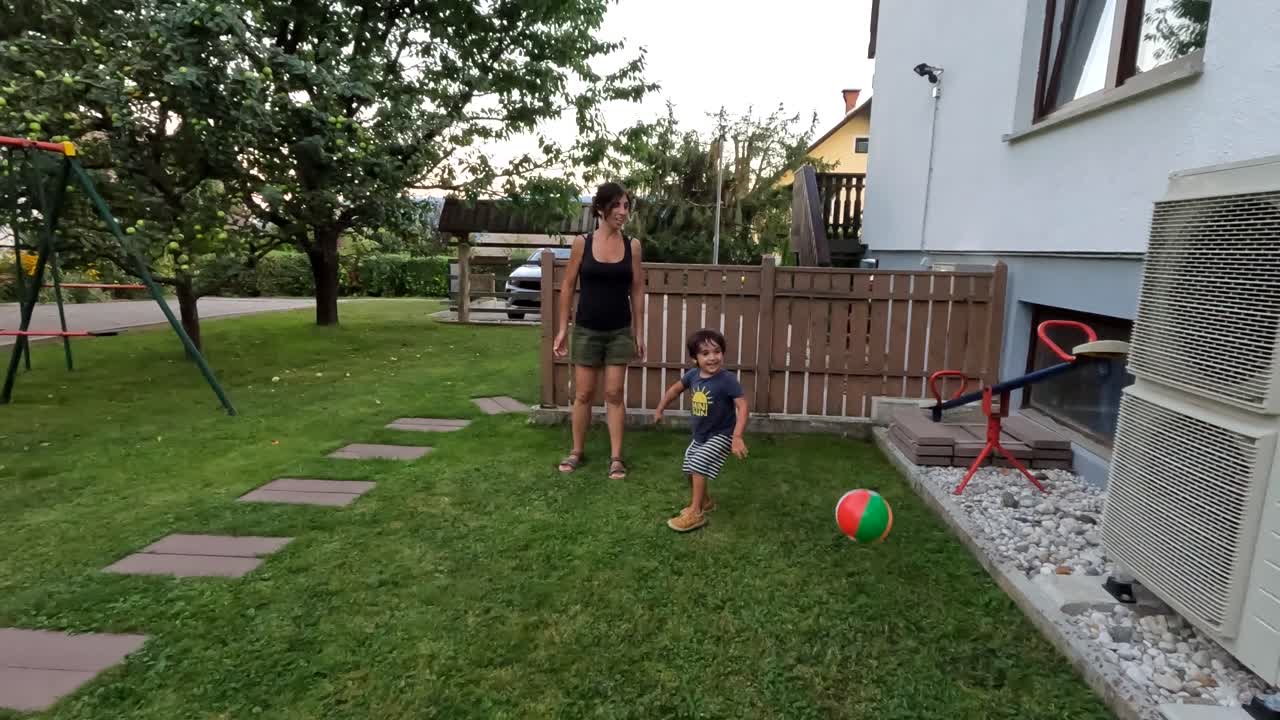 Woman and boy playing with a ball in the backyard