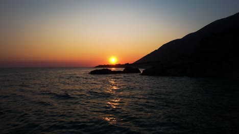 sunset on the rocky coast of the ionian sea as the sun fades behind silhouetted cliffs