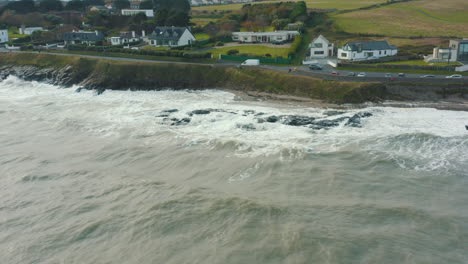 aerial view of waves crashing against rocks along the coastline during a storm