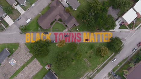 bird eye view of a large "black towns matter" sign painted on street in houston historical independence heights district