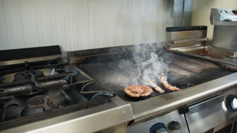 meat cooking on the professional kitchen griddle and releasing smoke