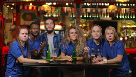 emotional fans in blue shirts at a beer bar. a multi-ethnic group of african-american people are upset and sad because of the failure of their team. defeat of your favorite football volleyball basketball hockey team.