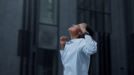 excited woman celebrating victory at modern glass building. achievement joy