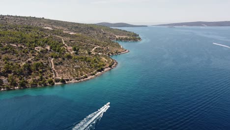 Cinematic-follow-aerial-shot-of-high-speed-boat-moving-along-the-coastline-of-Brac-Island,-Croatia