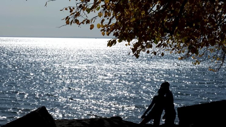 Bycylist along the shore of Lake Erie, silhouetted against the water kiss and walk off