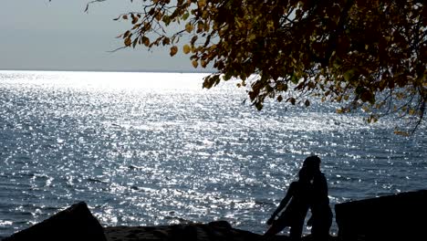 Ciclista-A-Lo-Largo-De-La-Orilla-Del-Lago-Erie,-Recortado-Contra-El-Agua,-Besa-Y-Camina