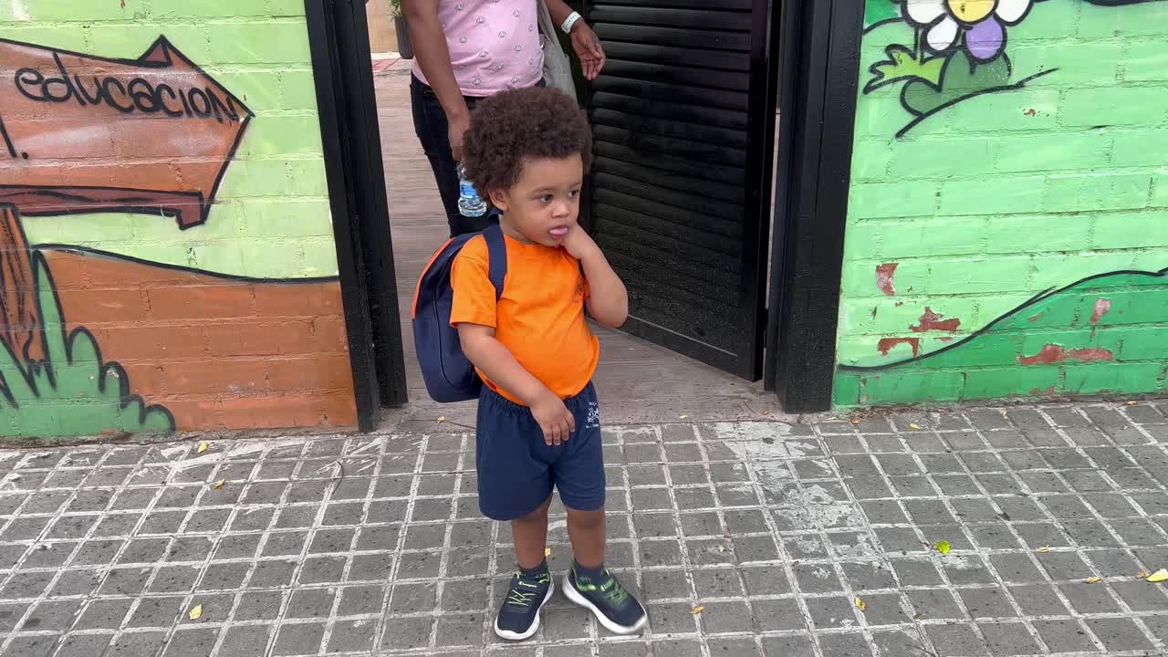 Adorable and shy two year old african european child a little upset after his first nursary day after summer vacations followed by mum