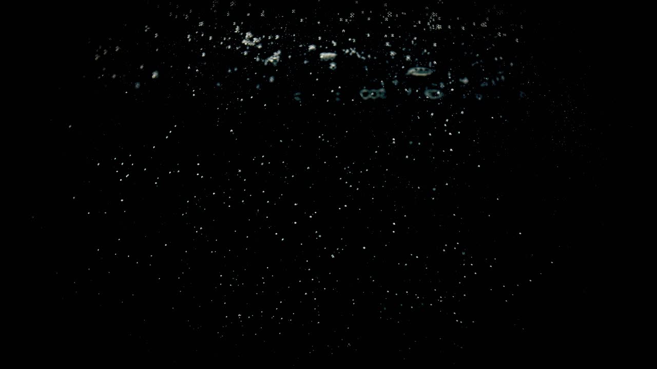 tomates cherry cayendo en agua sobre un fondo negro