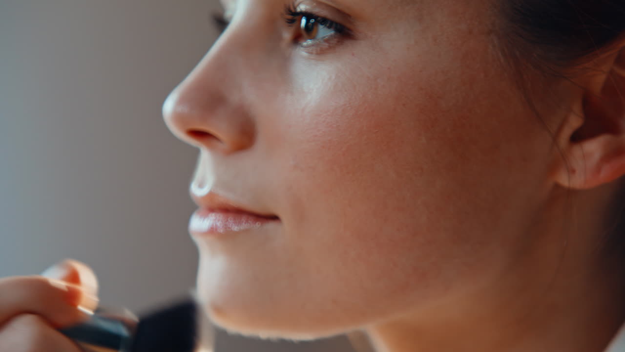 Closeup lady applying powder on healthy skin using cosmetic brush at home