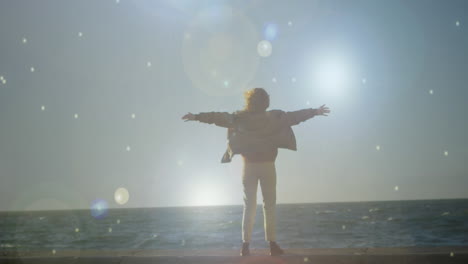 woman staring at the sea with arms wide open