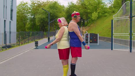 Active-elderly-old-sports-team-grandmother-grandfather-weightlifting-dumbbells,-smiling-at-camera