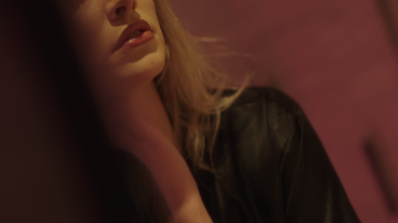 young beautiful blonde woman looks intensely in the mirror and plays with her bathrobe. beautifully made up