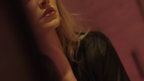 young beautiful blonde woman looks intensely in the mirror and plays with her bathrobe. beautifully made up