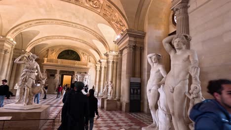 people walking through louvre's sculpture gallery