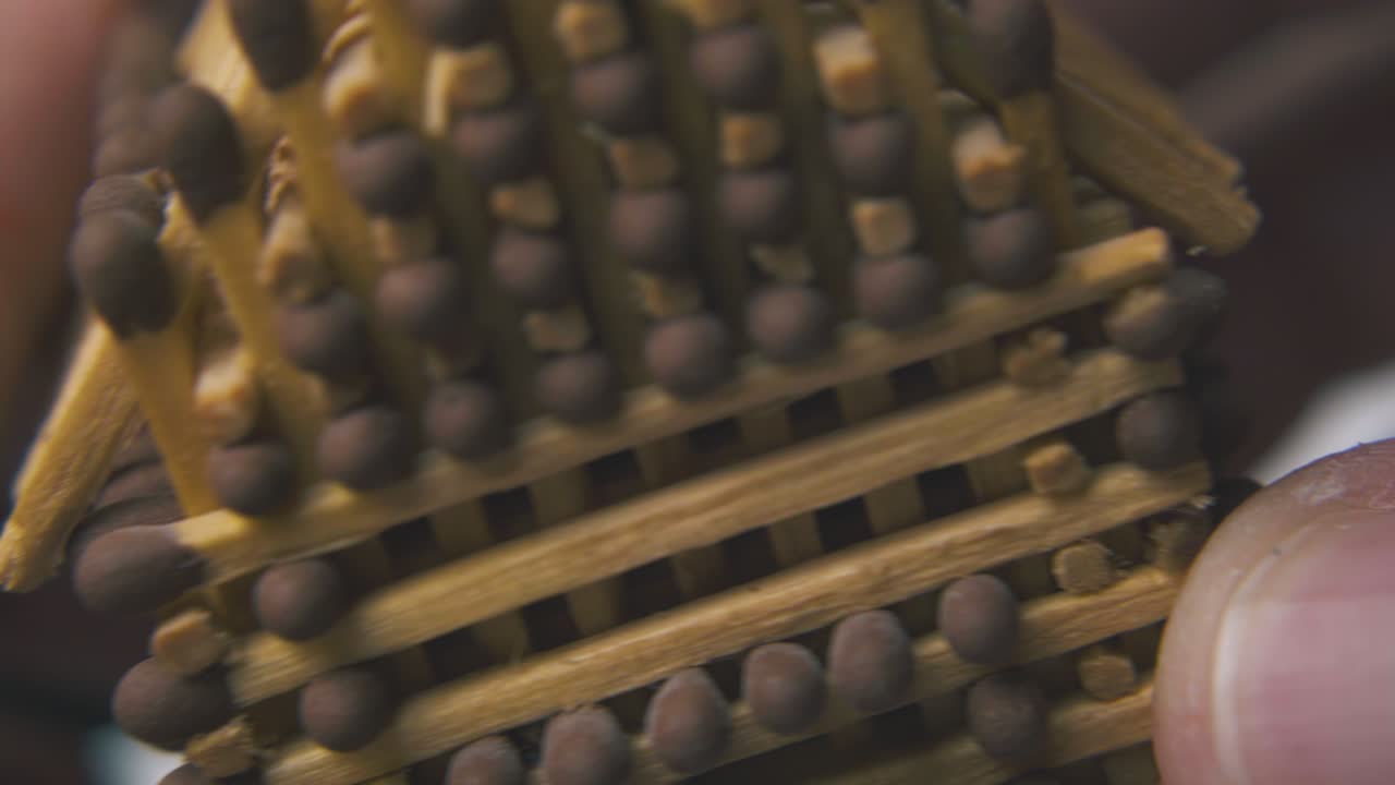 una persona muestra una casa hecha de fósforos en un fondo claro