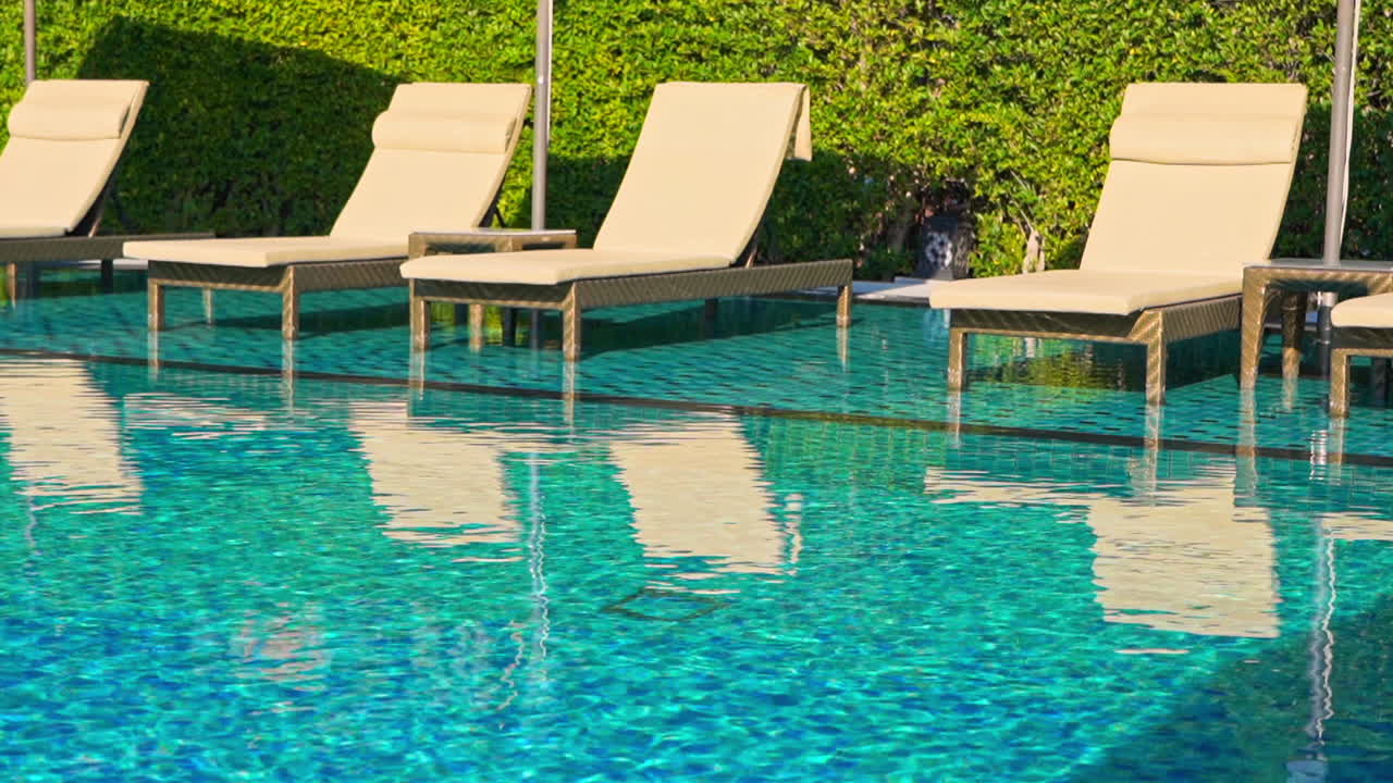 Tomme liggestole nær solrig, blå hotel swimmingpool