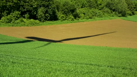 shadow on green field of a modern wind turbine generating clean energy, static