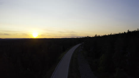 Empty-road-in-the-middle-of-forest-during-sunrise