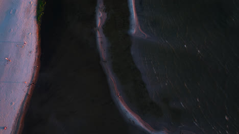 vista aérea inclinada sobre el agua iluminada por el sol y la arena en la costa de kalajoki, finlandia