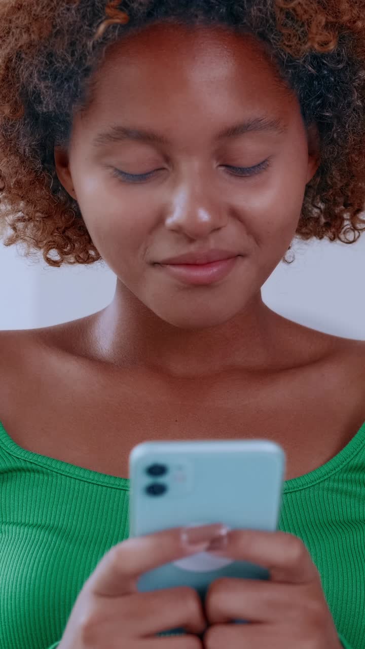 Young woman smiling while reading messages on a smartphone focused expression