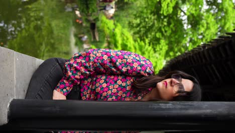 mujer con camisa floral sentada y admirando un jardín chino