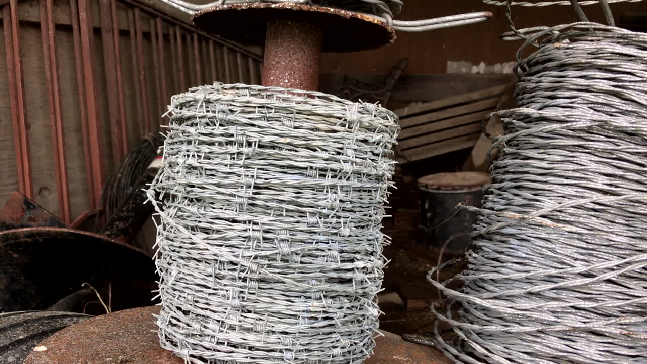 Pan from left to right of a spool of barbed wire in an old barn.