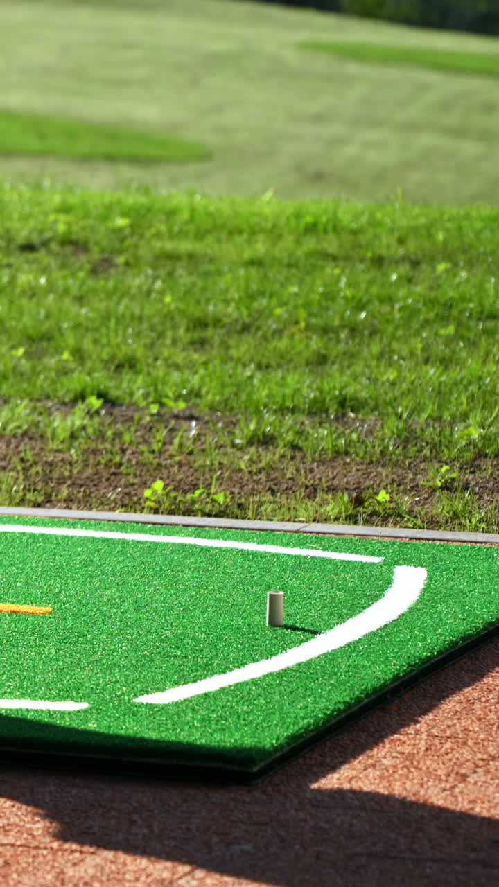 Close up of a golf club hitting a golf ball into a hole. Vertical