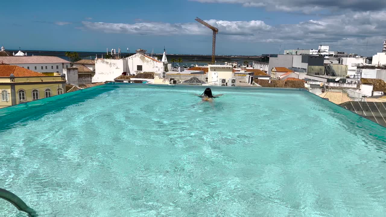 mujer nadando en una piscina del centro de la ciudad con agua caliente y cielo azul, concepto de viaje y vacaciones