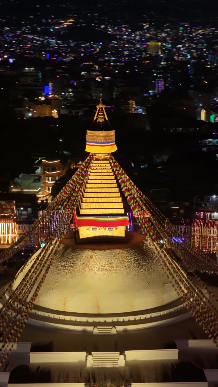 Kathmandu, Nepal, ripresa verticale 9:16 con drone del luminoso Stupa dorato di Boudhanath circondato da luci scintillanti della città e strade urbane decorate durante il Tihar