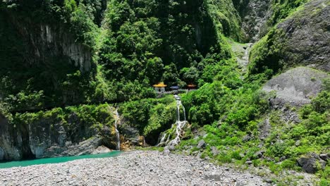 aerial flight towards waterfall and asian temple in taiwan nationalpark during bright sunny day