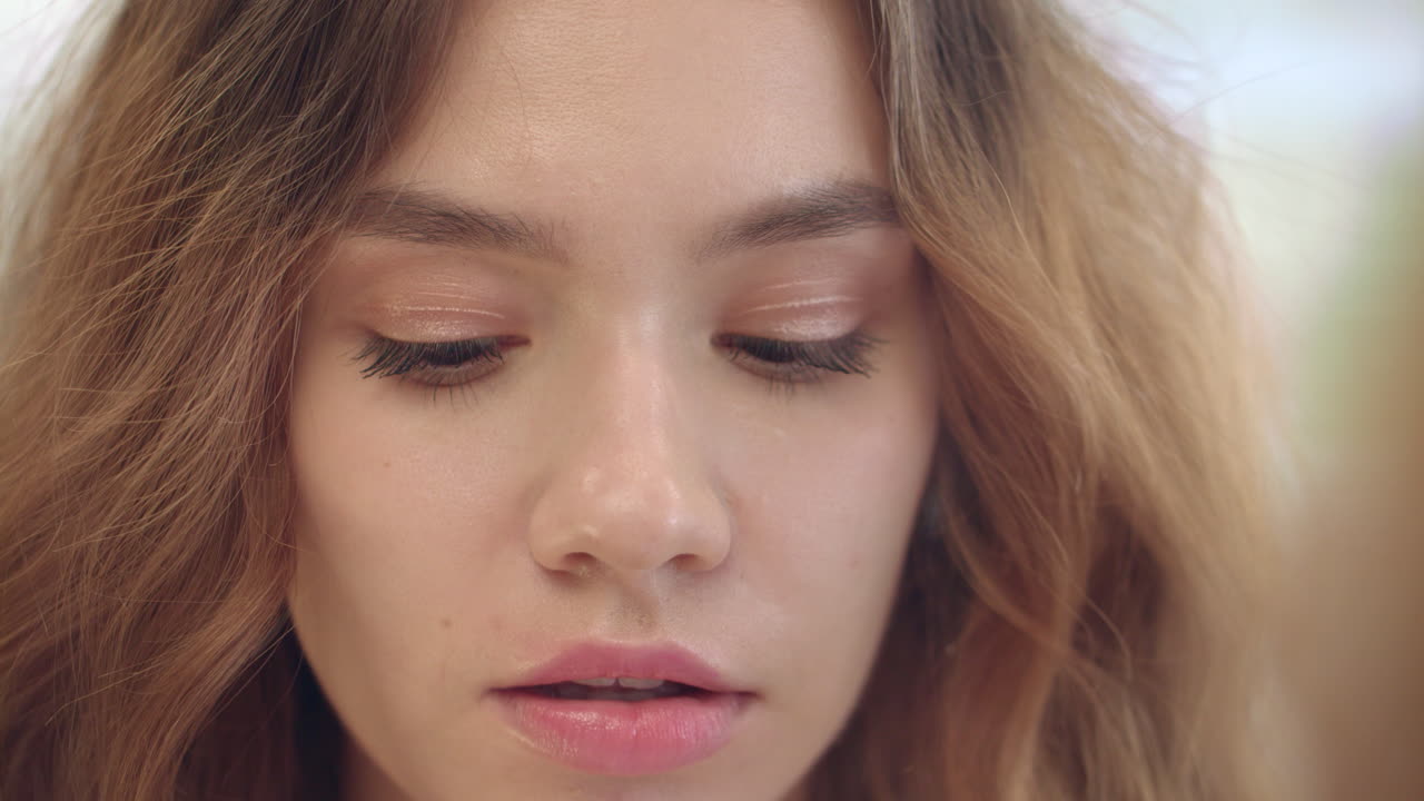 hermosa mujer aplicando crema a la piel mientras se maquilla en el espejo en el baño