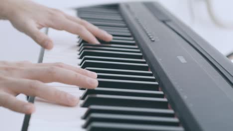 una niña toca el piano eléctrico, detalla las manos y las teclas