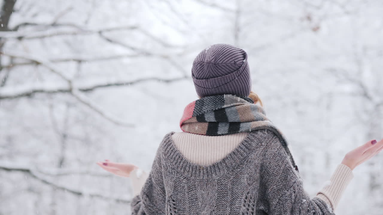 눈 덮인 겨울에 기뻐하는 여자는 손과 소용돌이로 눈송이를 잡는다