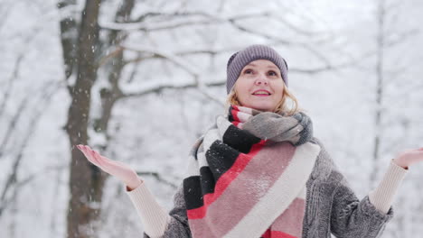 a woman rejoices in a snowy winter catches snowflakes with her hands and whirls