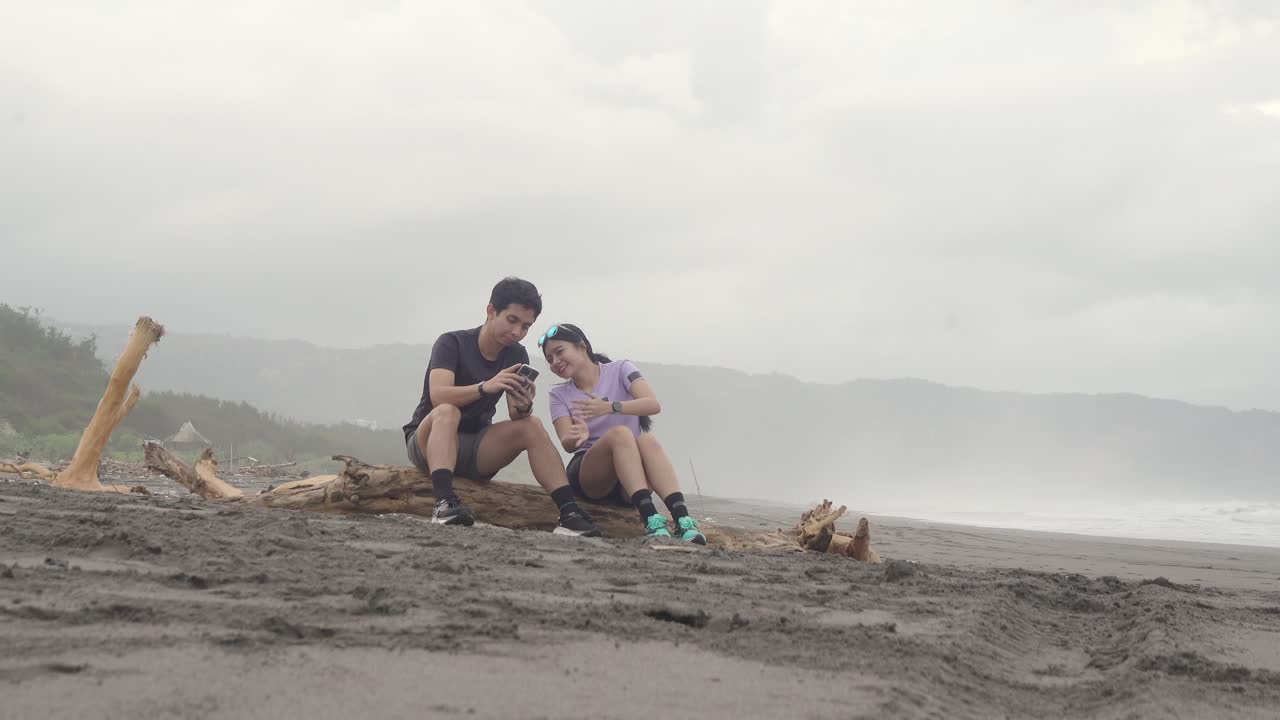 Couple Relaxing on Driftwood at the Beach