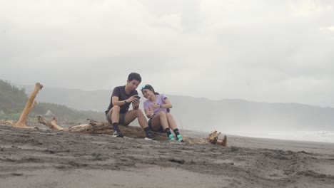 Couple Relaxing on Driftwood at the Beach