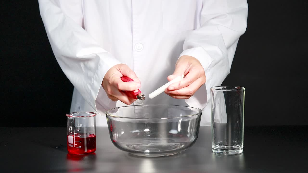 un científico lleva a cabo un experimento de reacción química con cera de vela, usando vasos y un cuenco de vidrio en un entorno de laboratorio