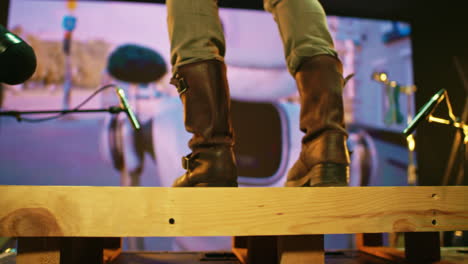 person in boots on wooden platform in recording studio